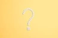 White pills arranged into a question mark shape on a vibrant yellow background.